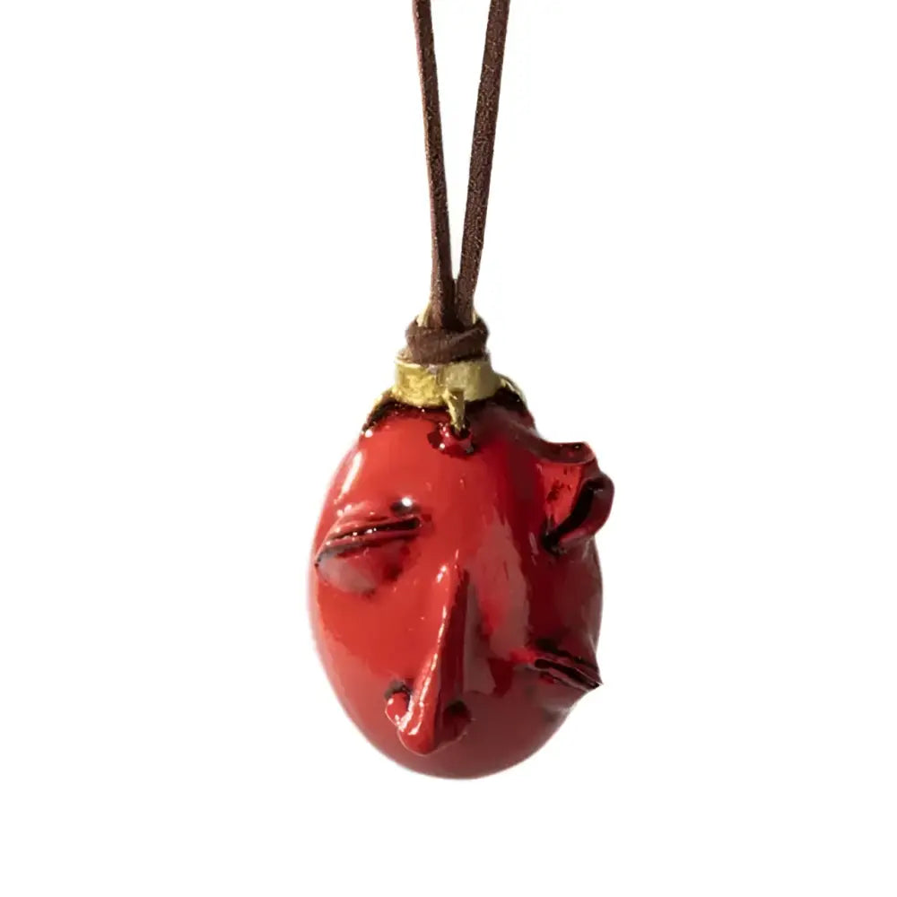 Glossy red resin pendant shaped like a stylized face from berserk griffith behelit pendant necklace with leather cord