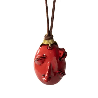 Glossy red resin pendant shaped like a stylized face from berserk griffith behelit pendant necklace with leather cord