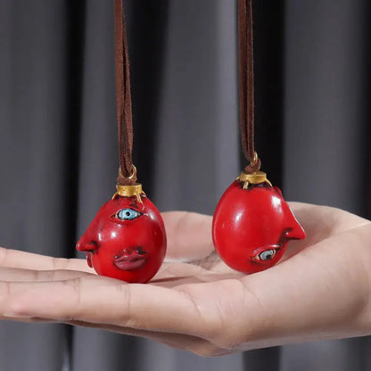 Two vibrant red glossy resin pendants with blue painted eyes and lips on brown leather cords necklace