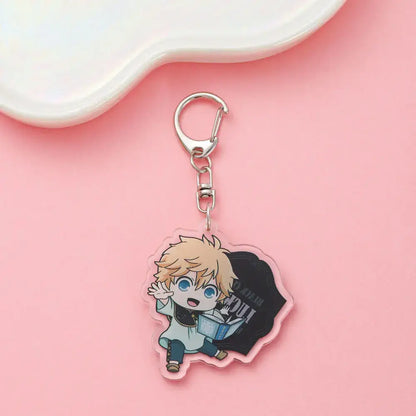 Clear acrylic black clover asta keychain with chibi blonde character holding a book on a black bag backdrop