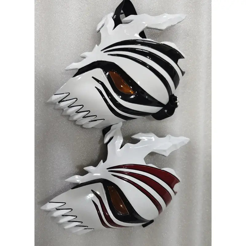 Two glossy white ichigo hollow masks with black stripes amber eye lenses and jagged edges for cosplay use