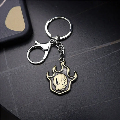 Metallic ichigo hollow mask keychain with a flame-shaped gold and silver pendant featuring an embossed skull design