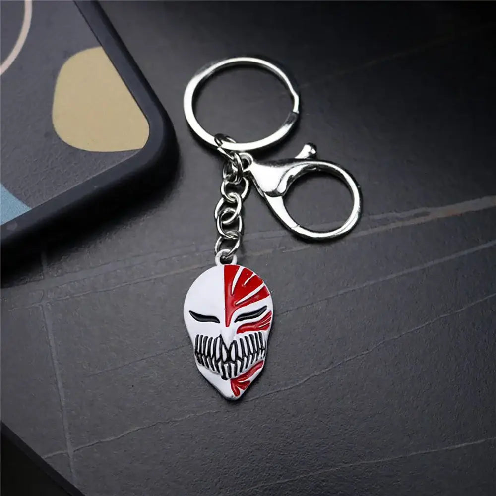 Silver-toned metal keychain featuring a white and red enamel ichigo hollow mask charm with black detailing