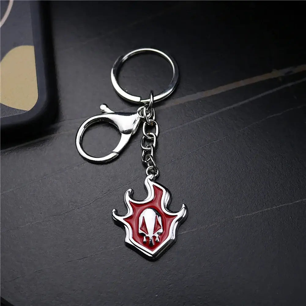 Red and silver metal bleach ichigo hollow mask keychain with a flame-shaped pendant and skull emblem center