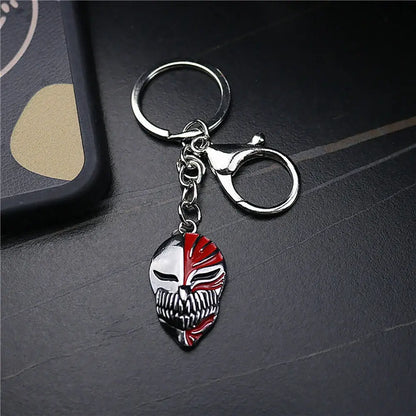A metallic ichigo hollow mask keychain with a split-face red and silver skull charm and lobster clasp attachment