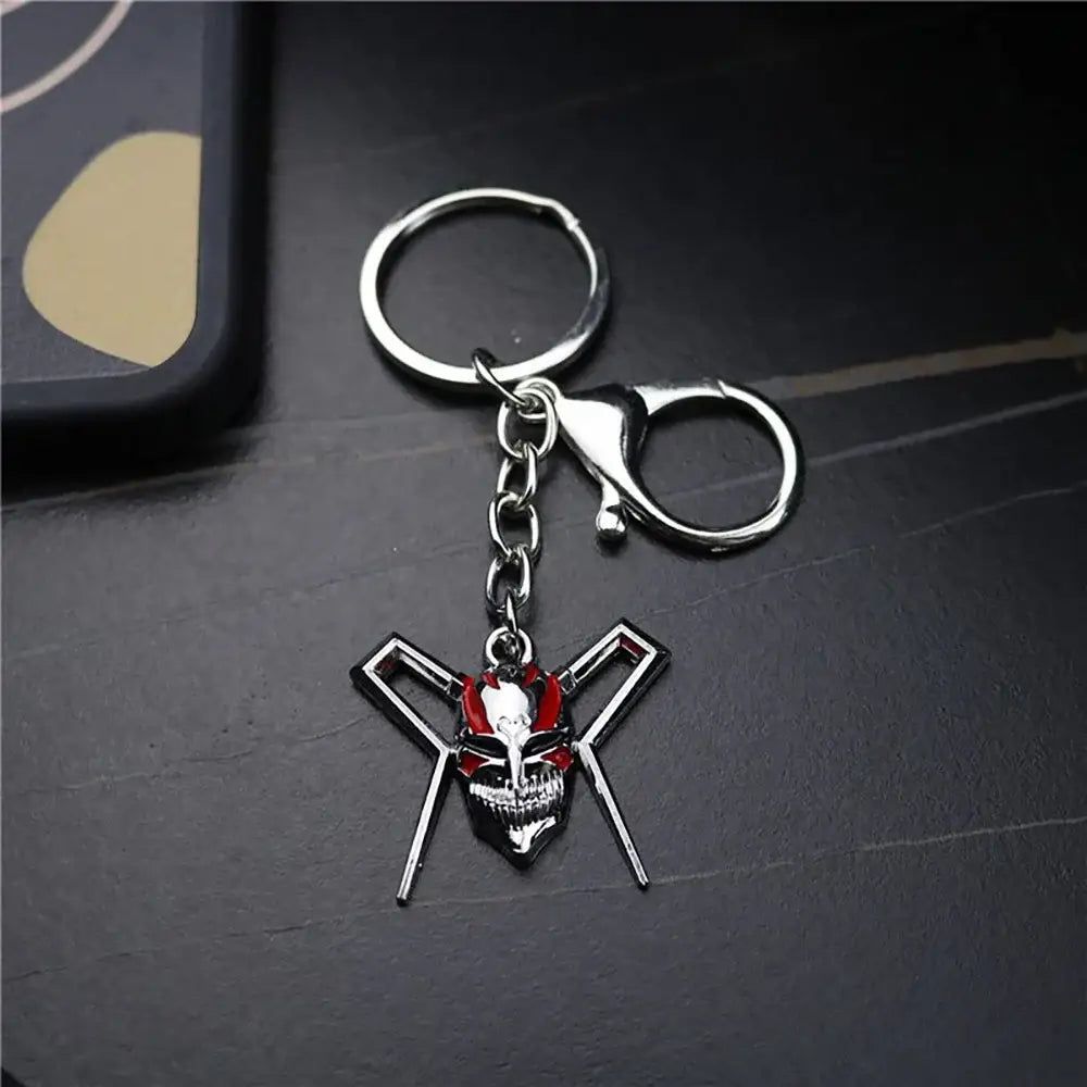 Silver metal keychain featuring a red and black ichigo hollow mask with crossed swords in bleach ichigo hollow style