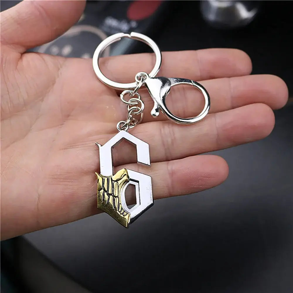 Silver and gold metal keychain with stylized g and detailed skull design featuring ichigo hollow mask elements