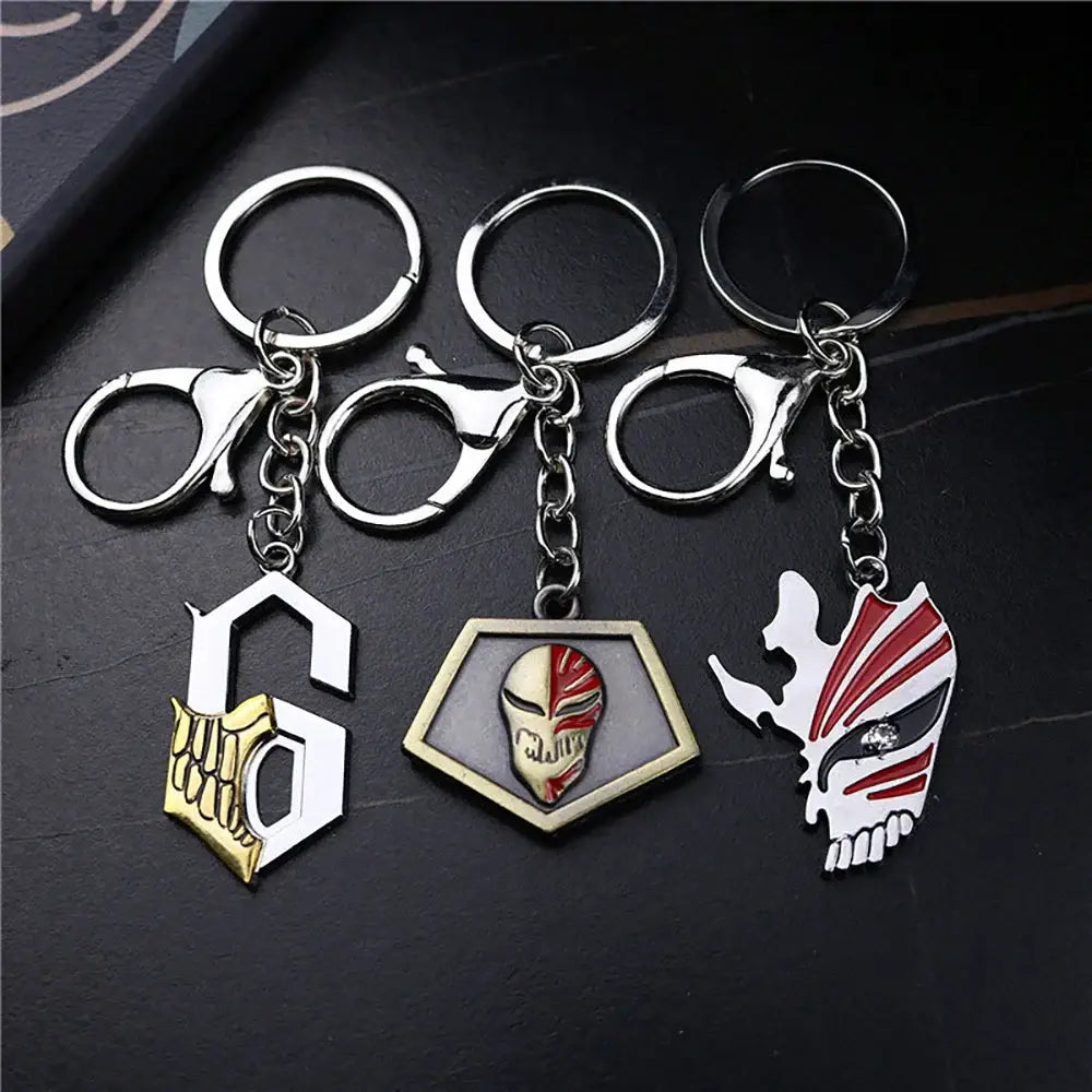 Three metallic bleacht ichigo hollow mask keychains featuring gold skeleton red white masked face and stylized skull mask designs