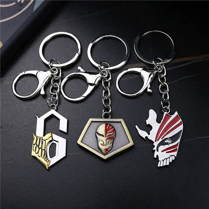 Three metallic bleacht ichigo hollow mask keychains featuring gold skeleton red white masked face and stylized skull mask designs