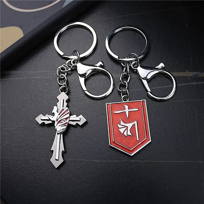 Two metallic ichigo hollow mask keychains featuring a silver cross with red white striped skull and red shield emblem