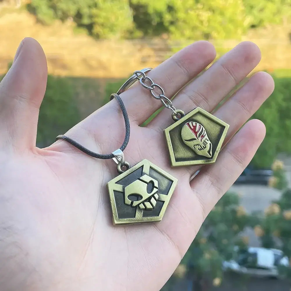 Two hexagonal brass-colored bleach ichigo mask necklaces made of durable zinc alloy with stylized skull designs