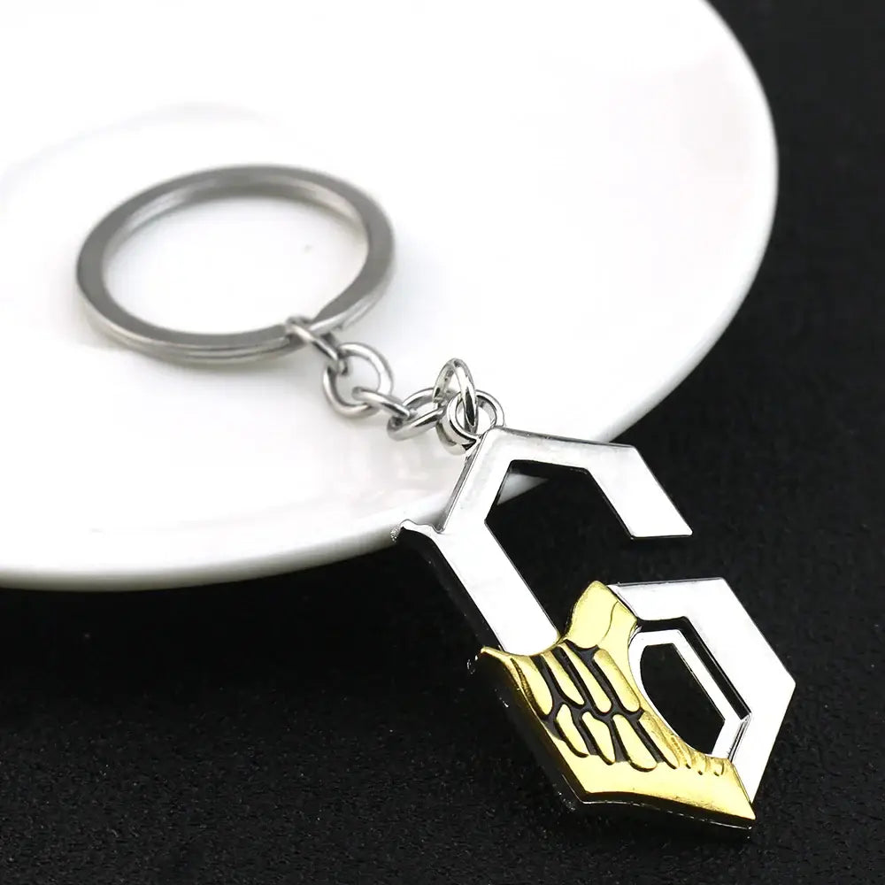 Silver and gold ulquiorra cifer metal pendant keychain featuring a stylized g with engraved skeletal hand design