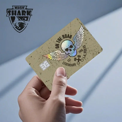 A tan distressed card skin featuring a holographic skull with wings and blue eyes white dragon text for l.a. use