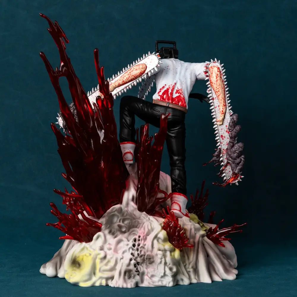 A 29cm pvc chainsaw man denji statue in a battle scene wielding two blood-splattered chainsaws in white and black clothing