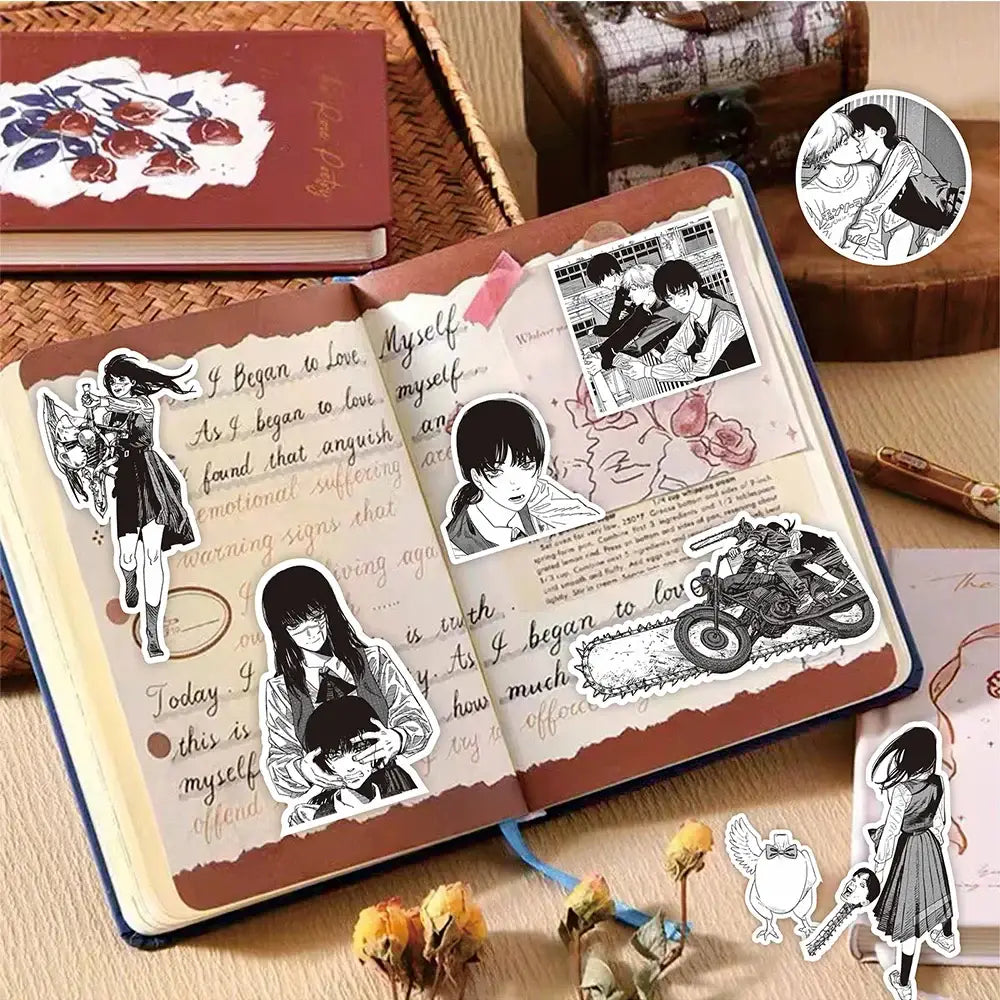 An open journal with a blue hardcover decorated with chainsaw man black and white manga style stickers