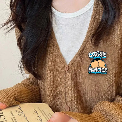 Blue and black cookie monster enamel pin cartoon brooch with cookie muncher design worn on brown knit cardigan