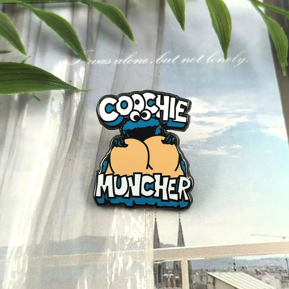 Blue and orange cookie monster enamel pin featuring cartoon character with cochie muncher text, monster enamel pin cartoon