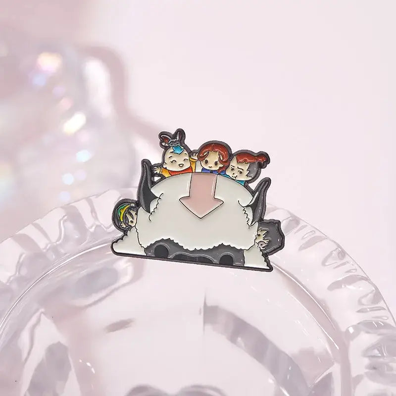 Colorful enamel pin featuring avatar the last airbender characters riding appa with pink arrow emblem, cartoon cattle style