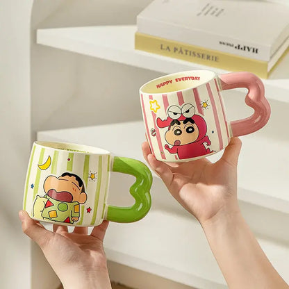 Two shin chan handle ceramic mugs with green and pink handles featuring cartoon designs and striped patterns
