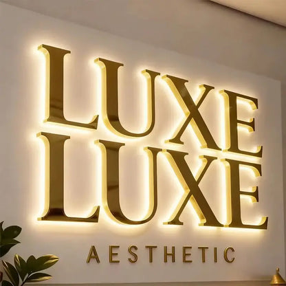 Gold-colored custom 3d led backlit sign with luxe luxe aesthetic lettering in waterproof metal mounted on wall