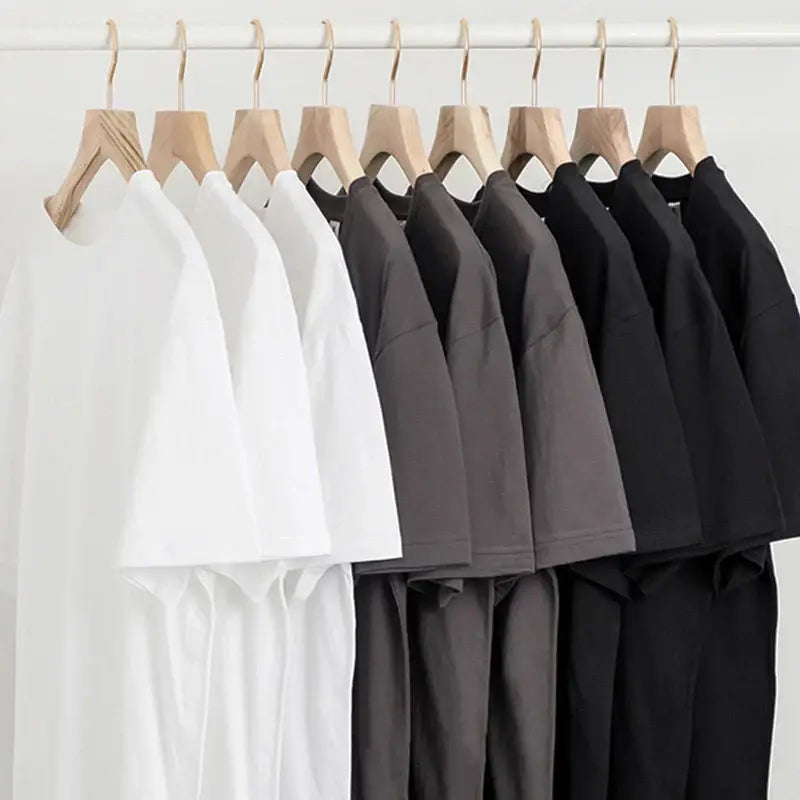 A row of custom graphic short sleeve tees in white gray and black on wooden hangers ideal for daily wear