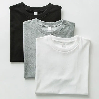 Three neatly folded custom graphic short sleeve cotton tees in black heather gray and white for daily wear
