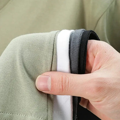 A hand holds a stack of olive green white and black cotton waistbands for a custom message unisex t-shirt 4XL-5XL
