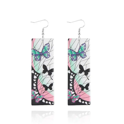Rectangular demon slayer tanjiro butterfly drop earrings with teal and purple butterflies on white acrylic surface
