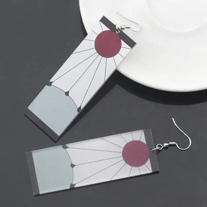 Rectangular acrylic demon slayer hanafuda earrings with maroon sun design and black radiating lines on white background