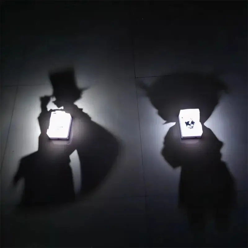 Two illuminated white detective conan goku projector lamps casting black silhouette shadows on a dark floor night light