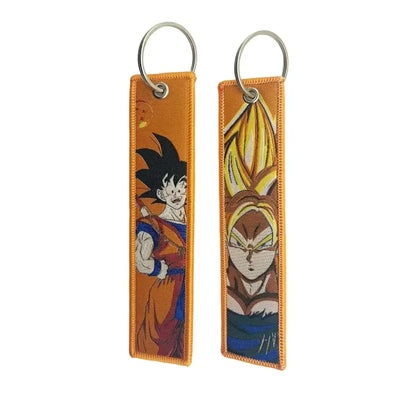 Two orange fabric dragon ball goku keychain holders featuring embroidered goku base form and super saiyan designs