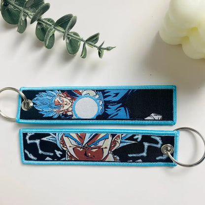 Two embroidered dragon ball goku keychain holders with blue and black fabric and silver metal rings