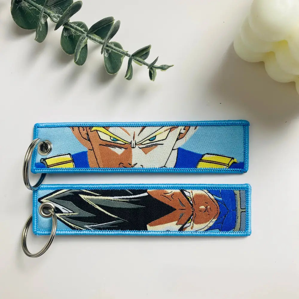 Two embroidered dragon ball goku keychain holders in blue yellow and black gray featuring anime designs