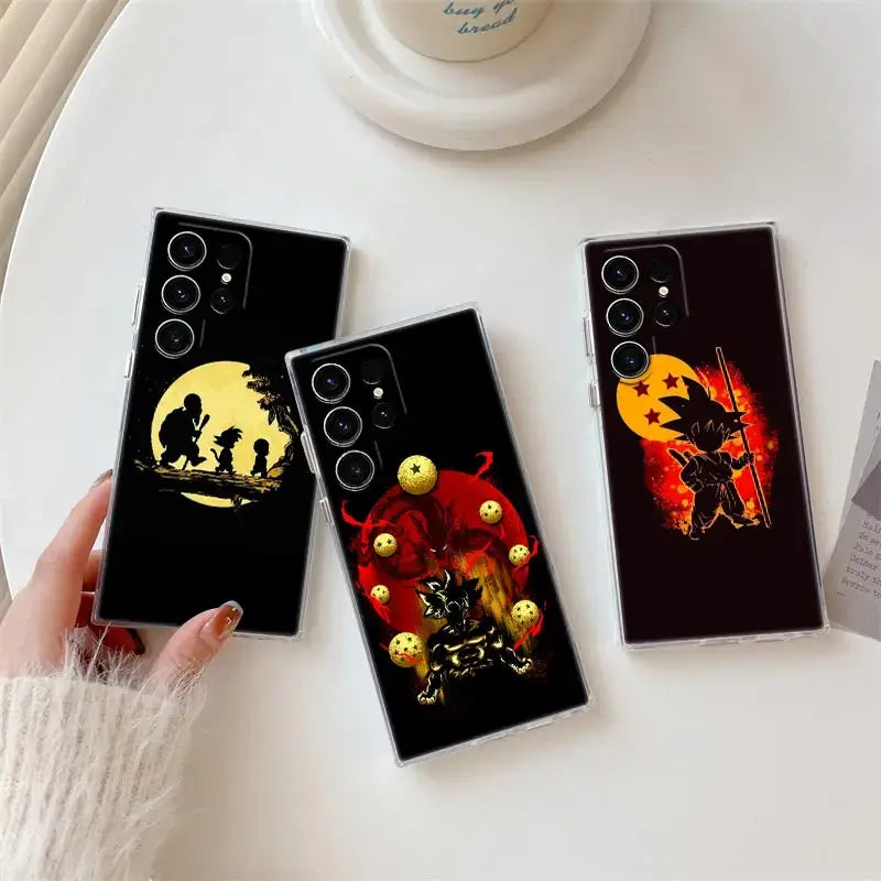Three black samsung ultra phone cases with dragon ball z goku silhouettes against yellow and red suns with golden spheres