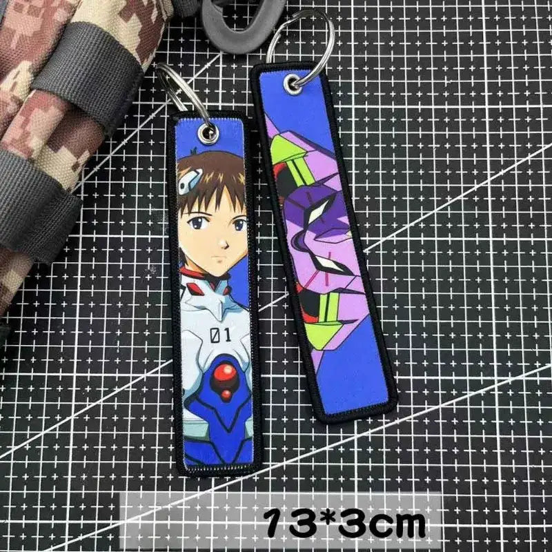 Two rectangular embroidered key tags featuring anime and mechanical designs in purple and blue, perfect as backpack charms