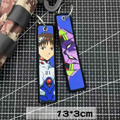 Two rectangular embroidered key tags featuring anime and mechanical designs in purple and blue, perfect as backpack charms