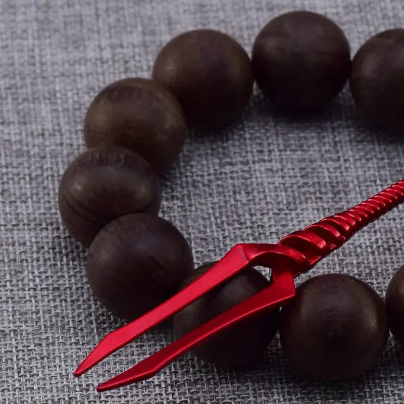 A vibrant red twisted metal evangelion spear 12cm pendant rests atop a string of dark brown wooden beads longinus keychain