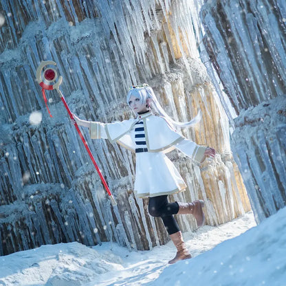A red and gold gem-encrusted staff held by a cosplayer wearing a frieren costume set with grey ponytail wig in icy cavern