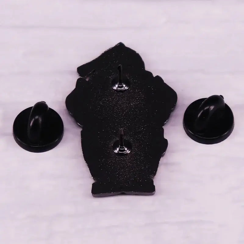 Black enamel alphonse elric enamel pin shaped like stylized bear with two silver fasteners on the back