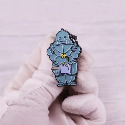 A light blue alphonse elric enamel pin featuring a cartoon iron giant holding a yellow cat with metallic details