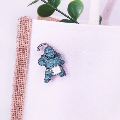 Teal enamel alphonse elric pin badge featuring a stylized armored character with a white apron and curved metal clasp
