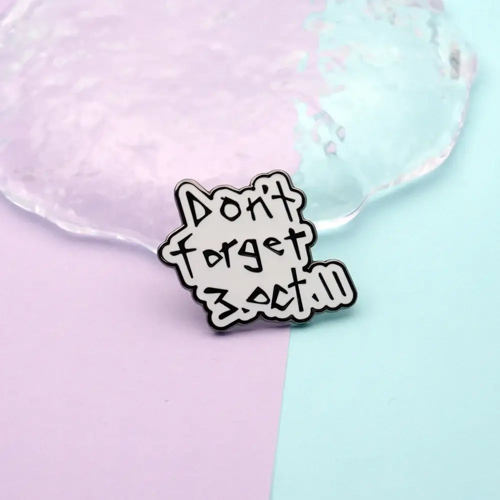 White enamel pin with black text dont forget 3.oct and scalloped edge featuring fullmetal alchemist edward elric design