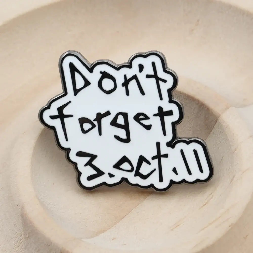 White enamel pin with black outlined playful text reading dont forget 3.oct.11 from fullmetal alchemist edward elric