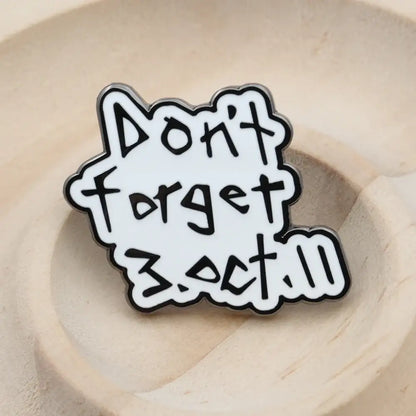 White enamel pin with black outlined playful text reading dont forget 3.oct.11 from fullmetal alchemist edward elric