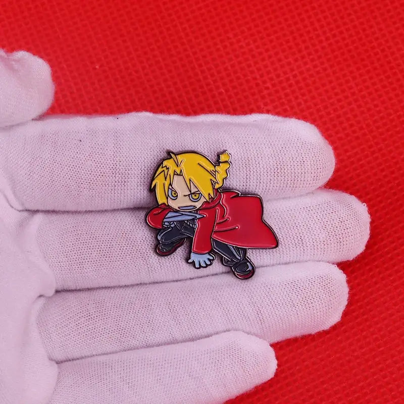 Red and gold enamel pin featuring chibi fullmetal alchemist edward elric with blonde pigtails and red coat