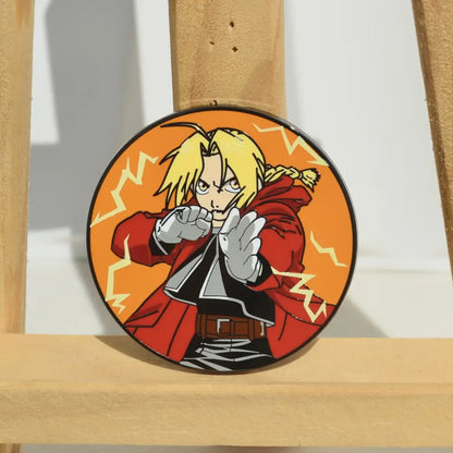 Circular metal badge enamel pin of fullmetal alchemist edward elric with blonde hair and red coat on orange background