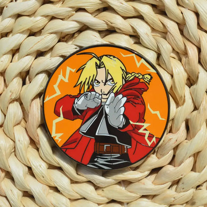 Circular metal badge enamel pin featuring fullmetal alchemist edward elric in red coat with lightning on orange background