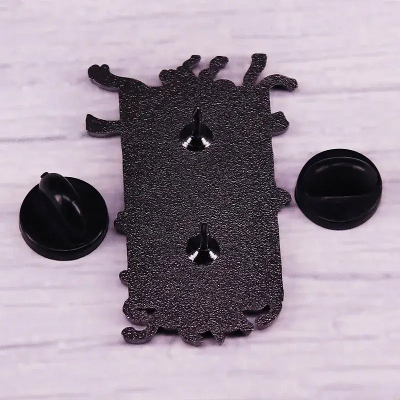Black glittery monster-shaped fullmetal alchemist gate of truth enamel pin with silver fasteners and black backing