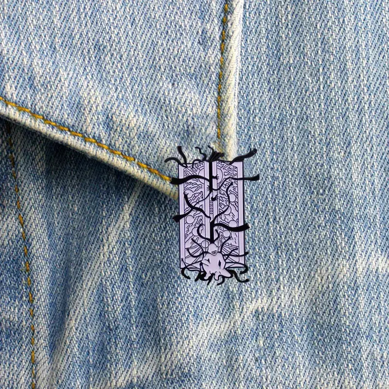 Purple enamel fullmetal alchemist gate of truth enamel pin with black octopus line art on light-wash denim fabric