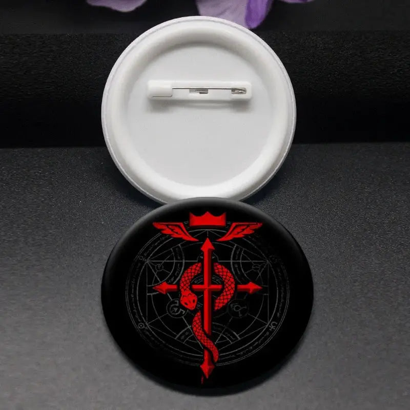 Black circular enamel pin featuring a red winged emblem with a crown inspired by roy mustang fullmetal alchemist